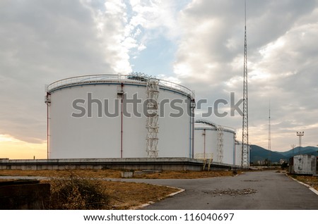 Metal oil tanks at sunset