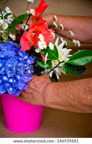 hands of an elderly woman making a bouquet of flowers