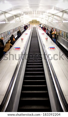 LONDON - OCT 24 2013: People commuting on a moving stairs, going up and down, in the London underground.