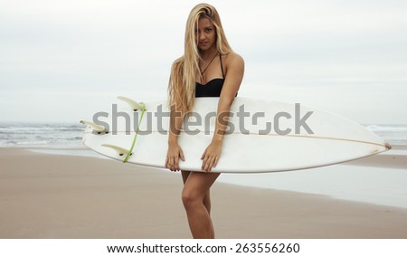 Pretty surfer girl on the beach with surfboard