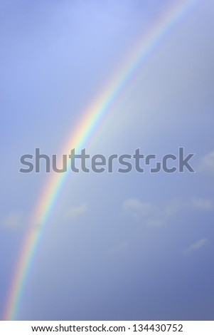 bright real rainbow in a partly cloudy blue sky