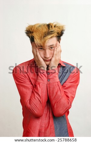 Tired confused guy with golden hairstyle in the red shirt hold his head