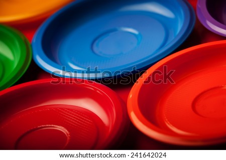 Colored plastic plates on red background