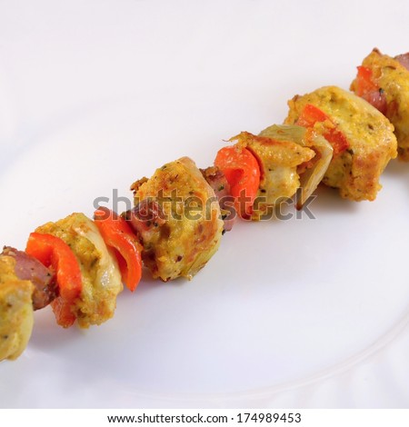 Chicken skewer with vegetables and sausage on a plate with a clean background