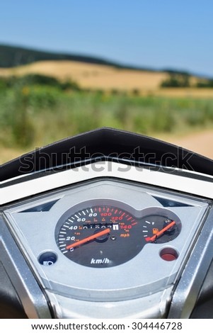 Tachometer on a motorbike (scooter)\
Natural blurred background landscape