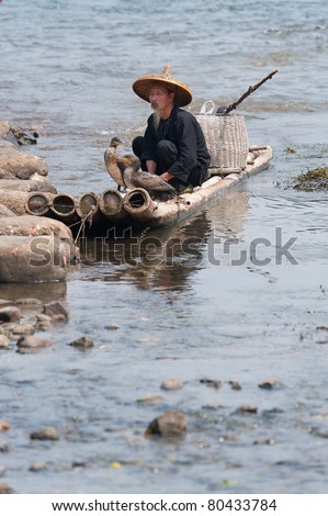 GUILIN, CHINA - OCTOBER 22: Unidentified elderly Chinese fisherman sitting on his boat October 22, 2008, Guilin, China. The cormorant birds are used as a tool for to help the fisherman.