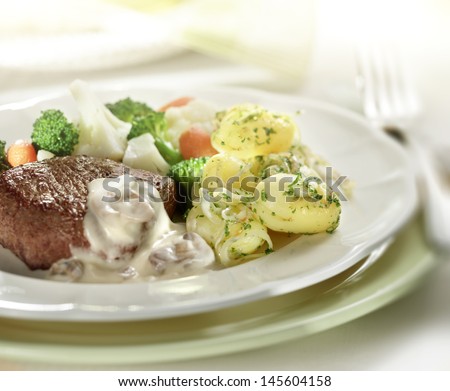 Steak served with potatoes, cauliflower with a sauce of mushrooms