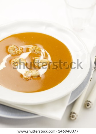 lobster soup with prawns and cream in it served in a deep plate with a spoon