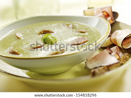 pea soup with smoked sausage and sprouts served in a bowl with brown toast and bacon