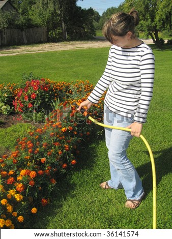 Young woman, watering the flowers in the yard