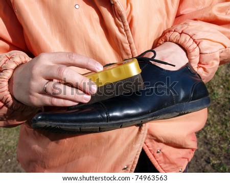 Hands cleaning or polishing black leather shoe