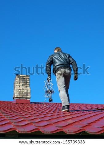 Man with special wire brush on roof clean chimney
