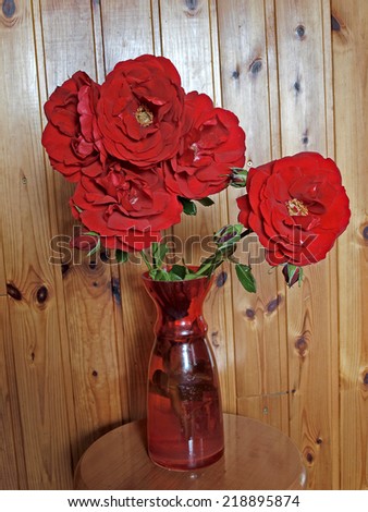 Red rose flowers in red glass vase