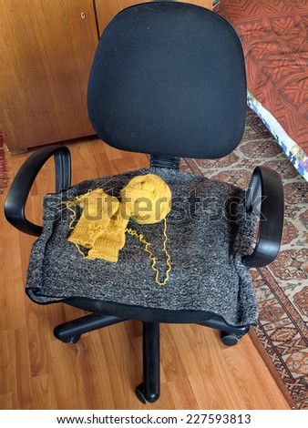 Knitting socks and yellow yarn ball on office chair