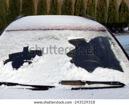 Snow covered car front window partly cleaned both sides, horizontal