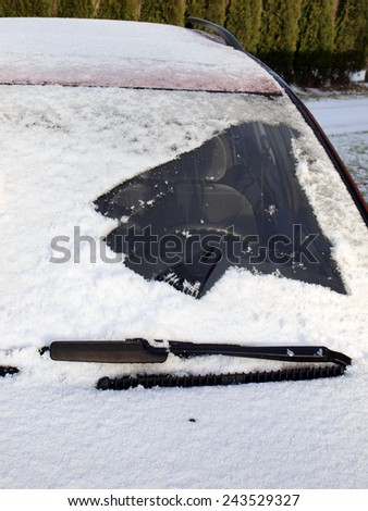 Left side of snow covered car front window partly cleaned, vertical