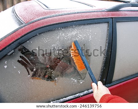 Hand with plastic brush clean ice from car side window