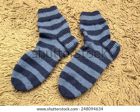 Dark and bright blue striped socks on soft carpet separately