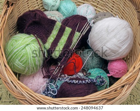 Wicker basket with knitting and yarn balls close up