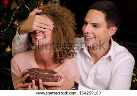 Husband playfully giving a special christmas gift to his beautiful wife