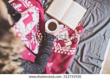 Soft photo of woman on the bed with cup of tea reading book, top view point