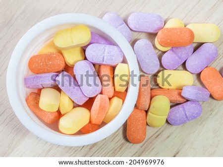 Colorful vitamin pills stored in a small cup