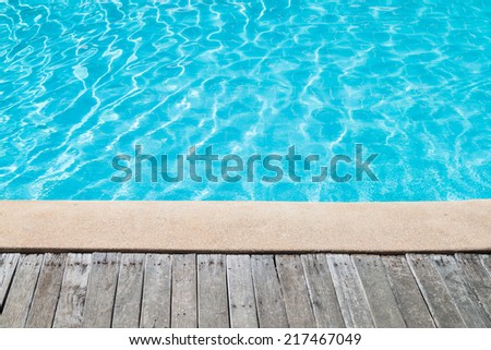 Swimming pool with concrete and wooden deck as a background