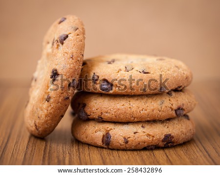 Dark chocolate chips cookies on a wooden table, warm tone style