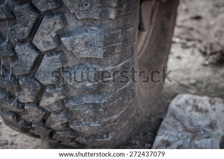 Close up of tire on heavy duty car with dirt road background