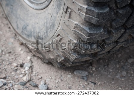 Close up of tire on heavy duty car with dirt road background