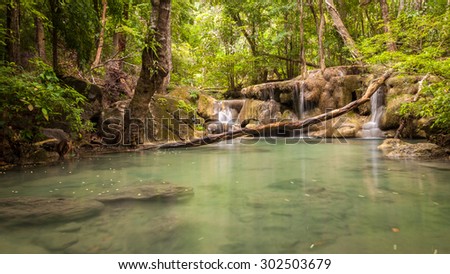The fifth level of Erawan waterfall in Thailand, old branch of tree falling in front of the waterfall