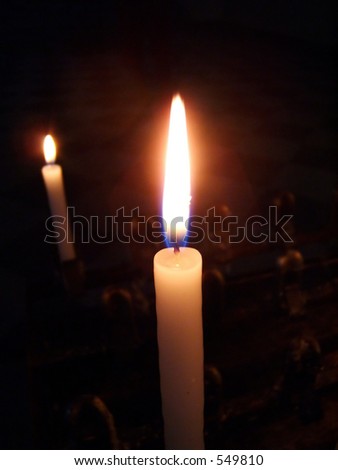 a typical votive candle in the darkness of a church, light up for a prayer
