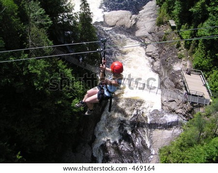 woman doing acrobranch sport  - walk with ropes and wires between trees in Ste Anne Canyon, Quebec, Canada