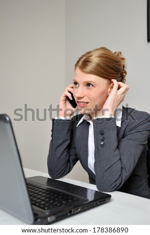 Red haired business woman having a difficult conversation behind her laptop at the office.