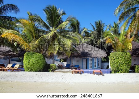 Beach bungalows with deck chairs on a tropical island, Maldives
