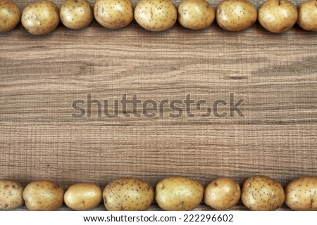 Beautiful frame with fresh potatoes on raw wooden background. Image of natural materials. Eco style.