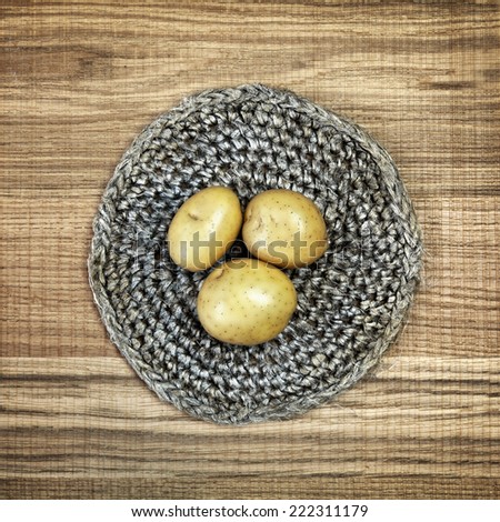 Beautiful decoration with fresh potatoes on linen doily. Image of natural materials. Eco style. Sweet square composition on raw wooden background.