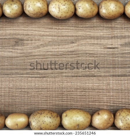 Beautiful frame with fresh potatoes on raw wooden background. Square image of natural materials. Eco style.