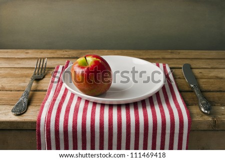 Red apple on white plate, table arrangement.