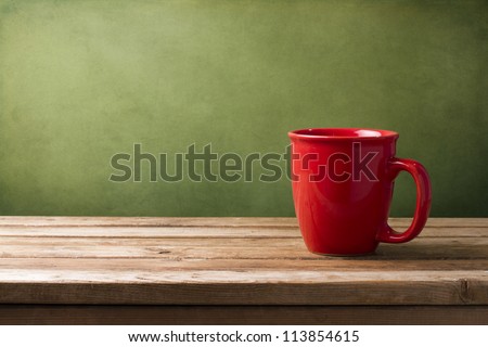 Red mug on wooden tabletop against grunge green wall