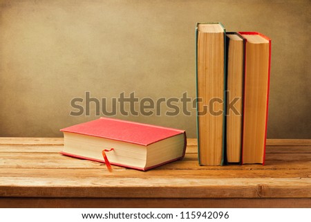 Vintage old books on wooden deck tabletop against grunge wall