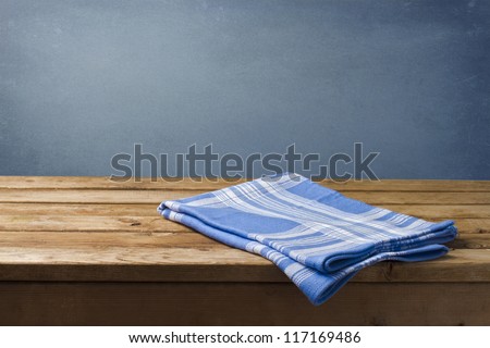 Background with wooden table, tablecloth and grunge blue wall