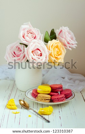 Still life with rose bouquet and macaroons on white table