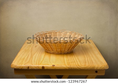 Empty basket on wooden table over grunge background