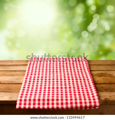 Empty wooden table with tablecloth over bokeh background