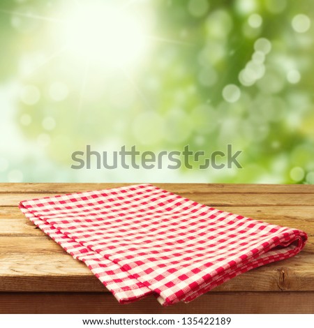 Empty wooden deck table with tablecloth over bokeh background