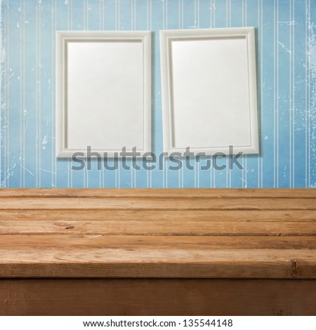 Empty wooden deck table over retro background with picture frames