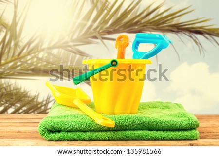 Beach items on wooden deck over palm tree branches