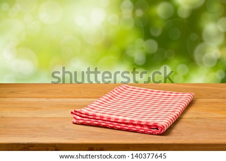 Beautiful background with empty wooden table and tablecloth over bokeh garden. Picnic table. Ready for product montage.