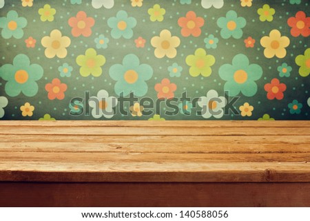 Empty wooden deck table over floral print wallpaper